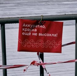 red and black wooden signage on wooden fence