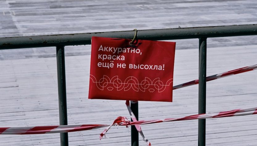 red and black wooden signage on wooden fence